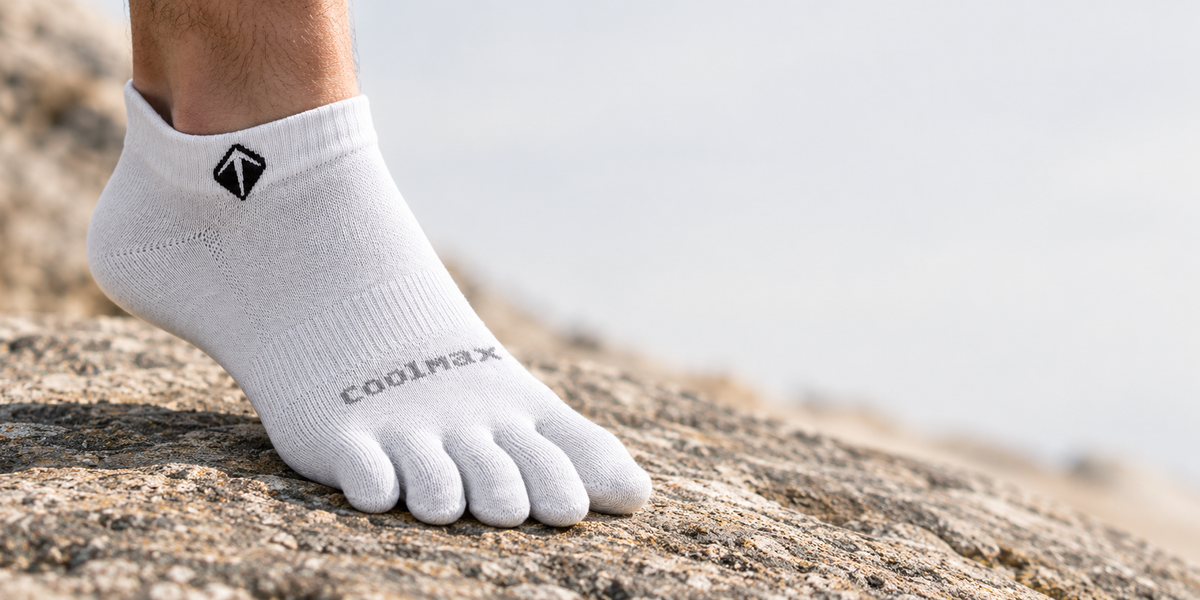 Foot in a five-toe sock splaying toes on natural ground